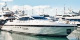 White and black yacht tied up in marina with other boats