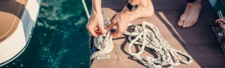 Man tying rope of a boat onto pier